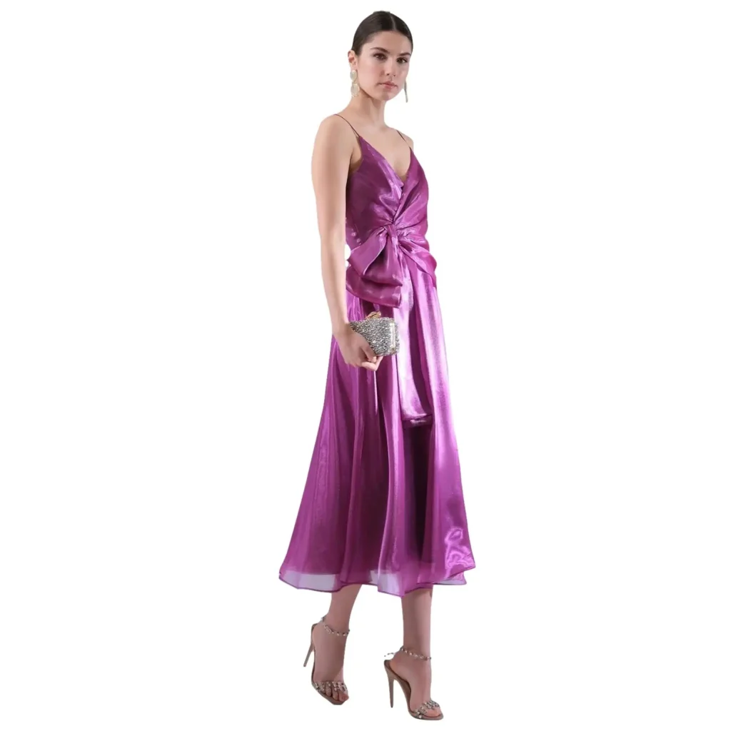 Shop the Elodia long bow dress in raspberry, a stunning evening gown made from luxurious organza fabric. This elegant dress features a flattering V-neckline, delicate spaghetti straps, and a dramatic bow detail at the waist, perfect for upscale events, galas, or parties. The flowing A-line silhouette offers comfort and style, while the shimmering fabric adds a touch of sophistication. Pair with sparkling accessories for a glamorous, high-fashion look.