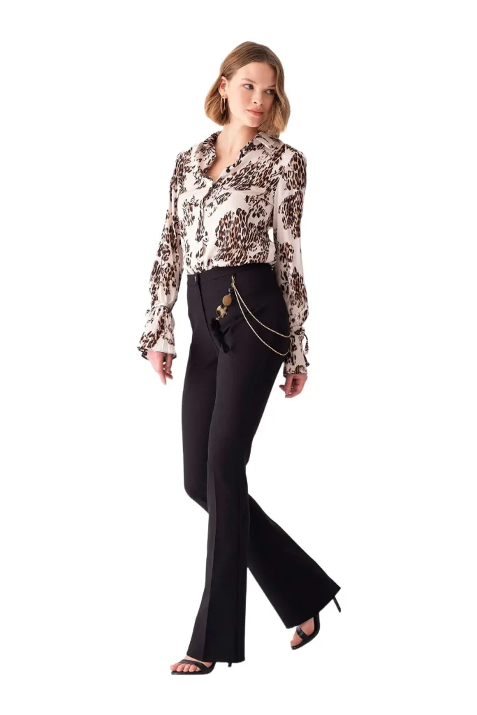 Shop Stelli comfortable stretchy black flare pants with chain detailing, perfect for business or casual wear, styled with a trendy blouse and sandals for a chic look.
