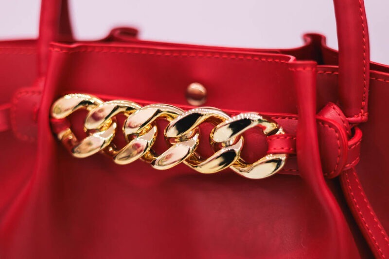 Anija red faux leather handbag with gold details, offering a luxurious and stylish design for a fashionable accessory.