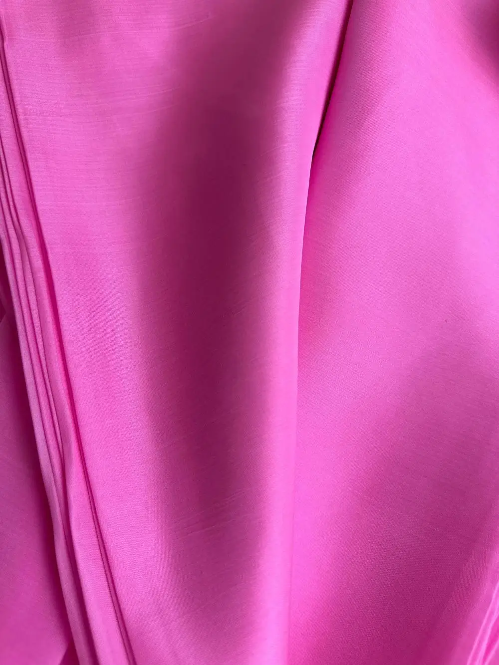 Close-up of raspberry Italian Mulberry Silk Satin with glossy surface and fine weave, perfect for dressmaking