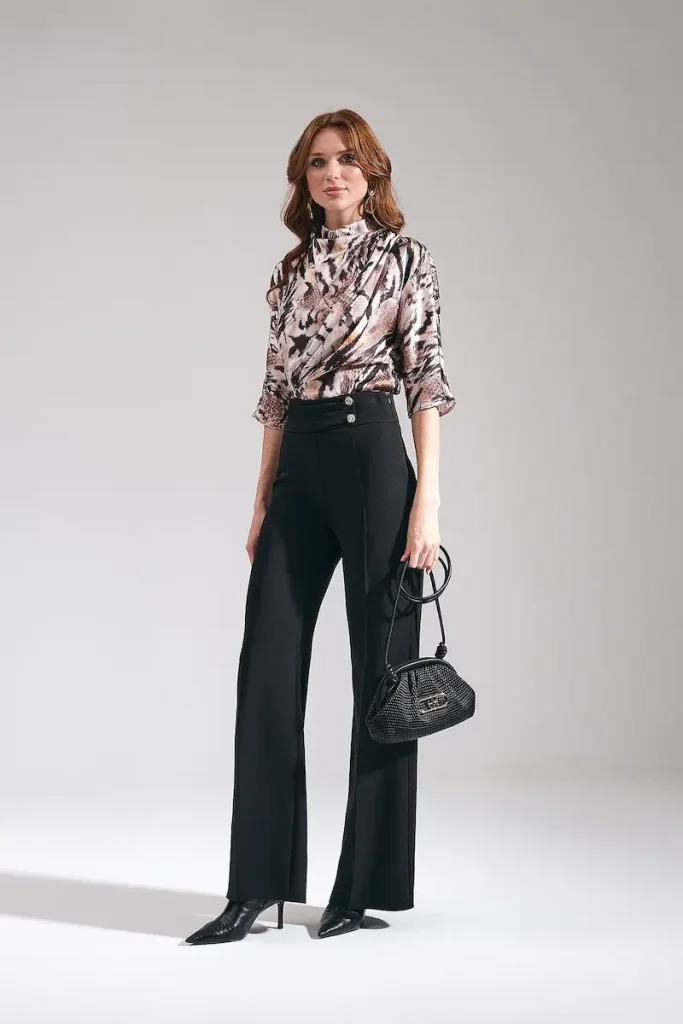Model wearing Maje women's high-waisted wide-leg trousers in black, styled as tailored work pants with an animal print blouse and black handbag.