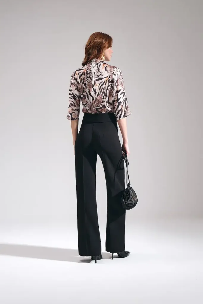 MOTRATi Model wearing Maje women's high-waisted wide-leg trousers in black, styled as tailored work pants with an animal print blouse and black handbag.